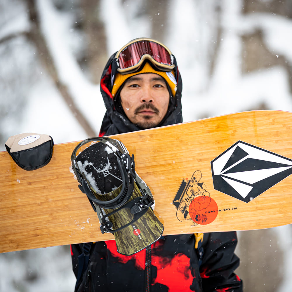 中井孝治さんがスノーボードを抱えて雪山にいる写真